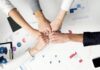 Free Colleagues celebrate success with a fist bump over financial charts depicting teamwork and unity. Stock Photo