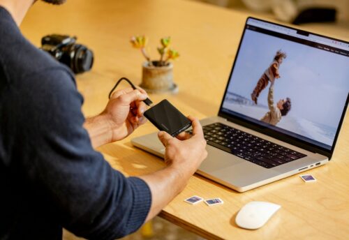A man sitting at a table with a laptop and cell phone
