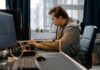 Free A concentrated professional working at a computer in a modern office setting. Stock Photo