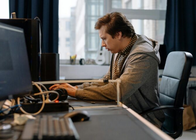 Free A concentrated professional working at a computer in a modern office setting. Stock Photo