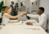 Free Business professionals completing a successful deal with a handshake in a modern office setting. Stock Photo