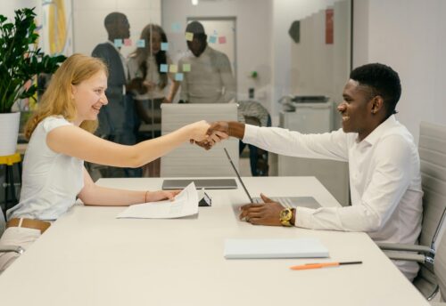 Free Business professionals completing a successful deal with a handshake in a modern office setting. Stock Photo