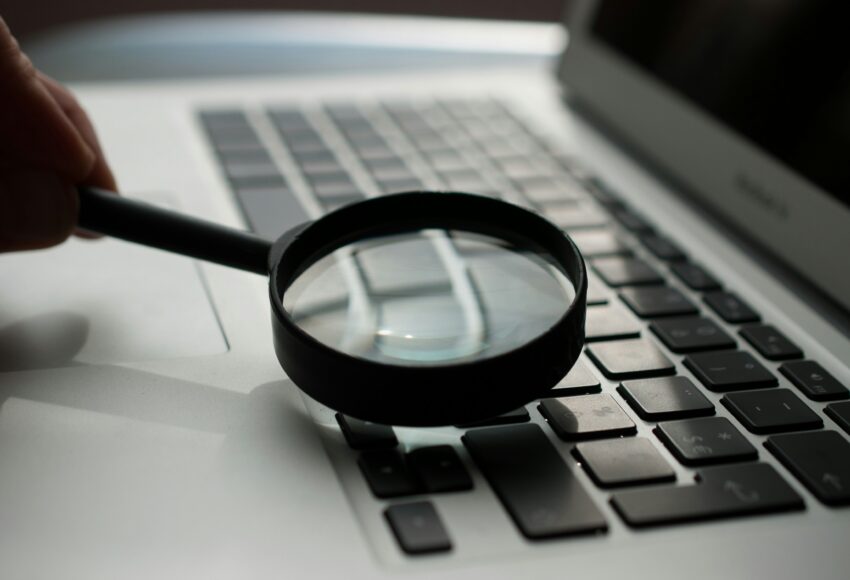 magnifying glass near gray laptop computer