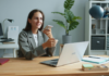lady holding phone while working on a laptop